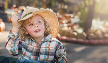 Cute young boy wearing cowboy hat at pumpkin patch farm