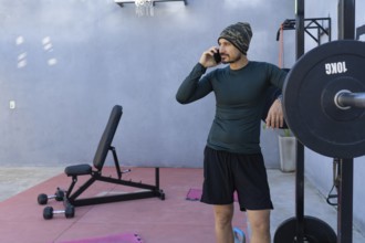 Athlete taking a break from an intense workout, leaning against a weightlifting rack while engaged