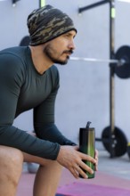 Athlete sitting and taking a break after an intense workout, holding a water bottle and emphasizing