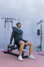 Athlete is strengthening his deltoids by performing seated lateral raises with dumbbells in an