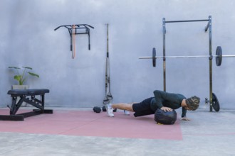 Young athlete performing push-ups with hands on a medicine ball in an outdoor gym, showcasing