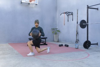 Athlete is performing lunges while holding a medicine ball in an outdoor gym, showcasing strength