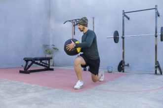 Athlete performing lunges while gripping a medicine ball in an outdoor gym, demonstrating strength