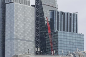 Mechanical red crane on a building in front of skyscrapers, City of London, England, United Kingdom