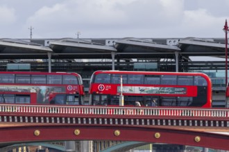 Two red double decker buses driving over a bridge, City of London, England, United Kingdom