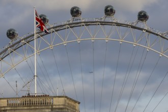 The London Eye wheel with a jet aircraft flying behind, City of London, England, United Kingdom