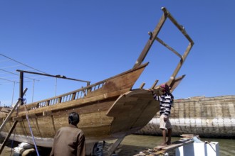 New dhow under construction, shipyard in Sur, two boat builders inspect the work progress, Sur,