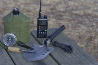Essential survival gear including walkie talkie, compass, folding shovel, and fire starter are