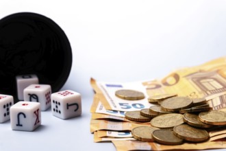 White dice with black letters and red dots are falling from a black dice cup, lying near some 50