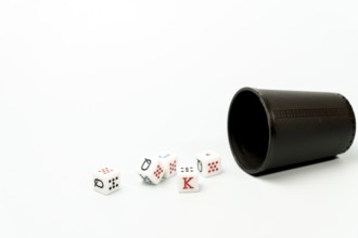 White poker dice with red and black markings rolling out of dark brown dice cup on white background