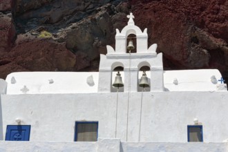 Agios Nikolaos Mavrorachidi, chapel with bell tower in front of red rock face, volcanic rock,