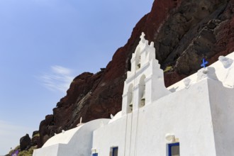 Agios Nikolaos Mavrorachidi, chapel with bell tower in front of red rock face, volcanic rock,