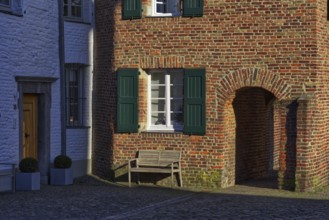 Red brick house with green shutters and bench in the shade, DÃ¼sseldorf