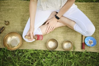 Overhead view of an unrecognizable person sitting cross-legged on a mat in a serene outdoor