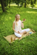 A woman engages in a calming meditation session, holding a singing bowl while seated on a mat in a
