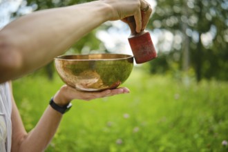 Engaging in meditation with singing bowls in a serene outdoor setting during daylight hours