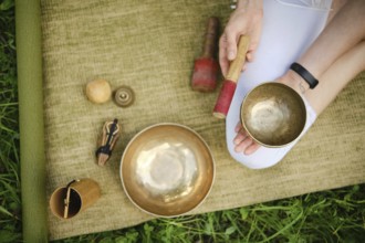 A mindful relaxation practice, playing singing bowls on a natural mat surrounded by grass, overhead