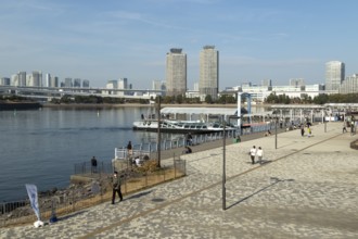 Strollers on the promenade and futuristic Tokyo Cruise Water Bus Queen Emeraldas, excursion boat