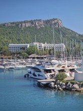 Kemer marina filled with numerous boats and yachts with Calis Hill in the background. A lighthouse
