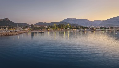 Dusk scene in Kemer, Turkey, showing the town illuminated coastline and beach, reflected