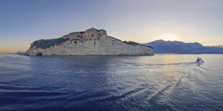Vibrant evening seascape with a boat cruising away on the blue sea, near the Pirate Cave in Kemer