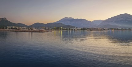 Dusk scene in Kemer, Turkey, showing the town illuminated coastline and beach, reflected