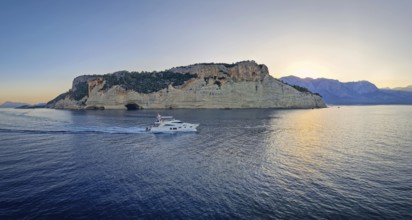Evening seascape panorama with a boat cruising away on the blue sea, near the Pirate Cave in Kemer