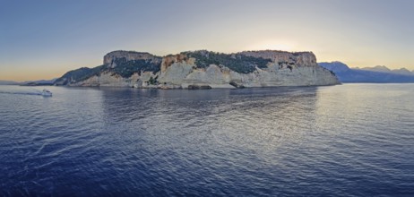 Evening seascape panorama with a boat cruising away on the blue sea, near the Pirate Cave in Kemer