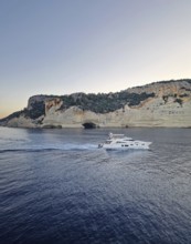 Vibrant evening seascape with a boat cruising away on the blue sea, near the Pirate Cave in Kemer