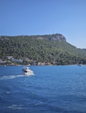 Vibrant seascape with a boat cruising away on the blue sea, leaving a white wake. Beautiful Turkish