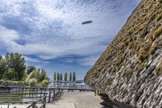 Thatched roof building with a view of trees and clouds in a rural setting, pile dwellings