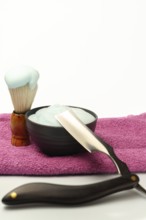 Shaving brush with foam, cream and straight razor are ready for a traditional wet shave