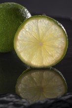 Three limes on a black stone plate with reflection