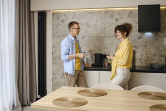 Married couple discusses plans for the near future standing in the kitchen in the morning