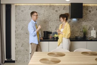 A man and woman talking in a stylish kitchen. They smile at each other, sharing ideas amidst fresh