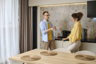 A couple engages in conversation near a kitchen counter, discussing ideas as they prepare for a