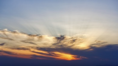 Sunset behind cloud cover, sunbeams, Oia, Thira, Santorini, Cyclades, Greece