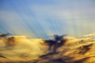 Sunset behind cloud cover, sunbeams, Oia, Thira, Santorini, Cyclades, Greece