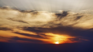 Sunset behind cloud cover, sunbeams, Oia, Thira, Santorini, Cyclades, Greece