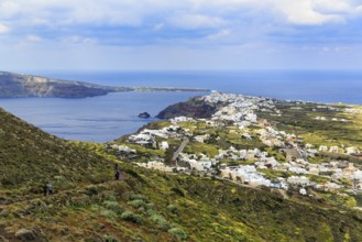 Coastline with view of the village of Oia, hiker on hiking trail from Fira to Oia, Thira,