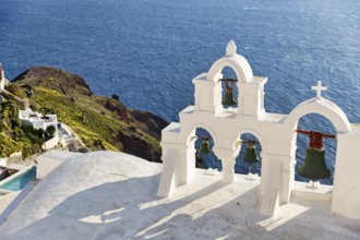 White bell tower of an orthodox church overlooking the sea, coastline, Oia, Santorini, Cyclades,