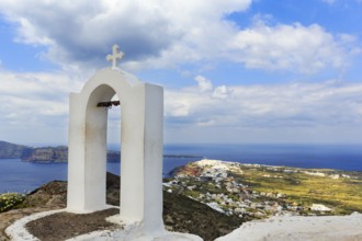 Love locks on the bell tower of an orthodox church, coastline, Oia on the horizon, hiking trail