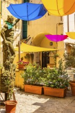 Coloured umbrellas cover a bronze statue in Via Cavour, Capoliveri, Elba Island, Tuscan Archipelago