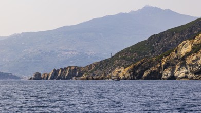 Rocky cliffs near Marina di Campo, in the background in the haze the peak of Monte Capanne, Elba