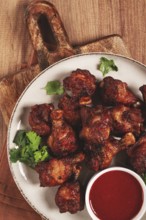 Juicy fried chicken pieces, served with spicy dipping sauce, on a rustic wooden table