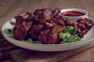 Juicy fried chicken pieces, served with spicy dipping sauce, on a rustic wooden table