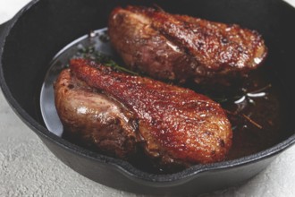 Roast duck breast, in a frying pan, with spices and herbs, close-up, no people