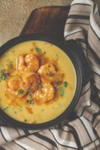 Creamy shrimp curry with spices, garnished with herbs, on a textured background, homemade, no