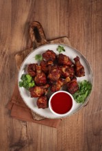 Juicy fried chicken pieces, served with spicy dipping sauce, on a rustic wooden table