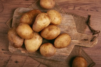 Raw potatoes, scattered on a chopping board, close-up, no people